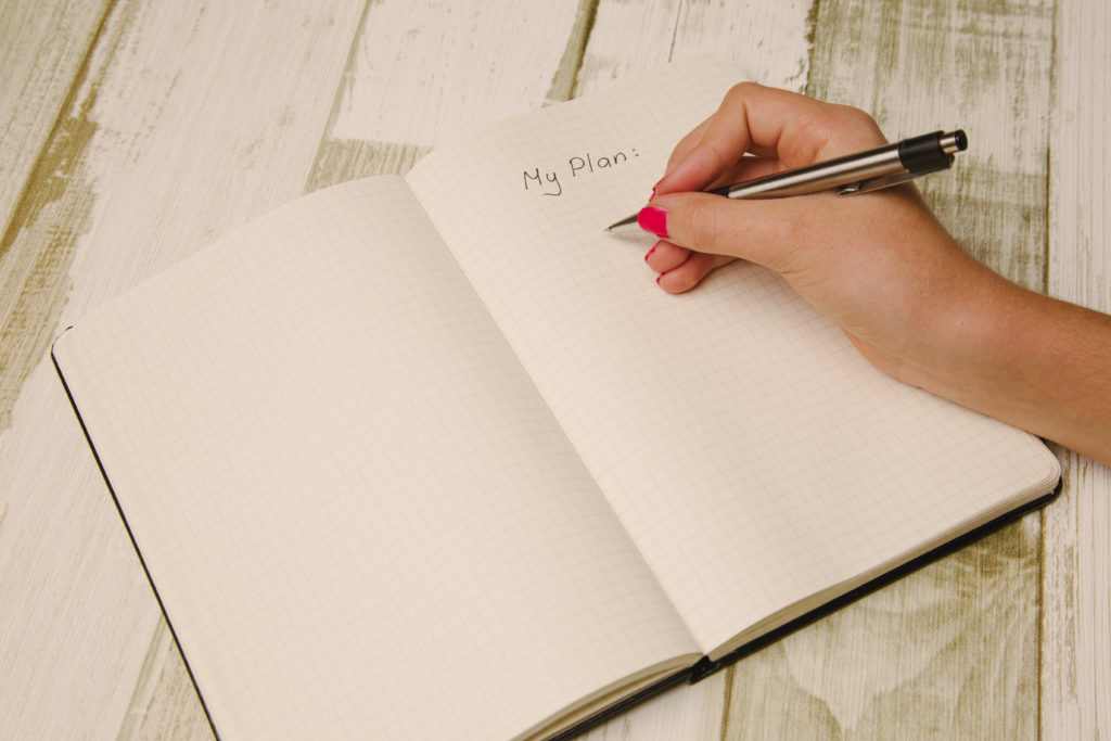 Female hand holding a pen and writing in a planner
