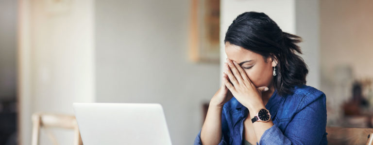 woman sitting at a laptop looking frustrated