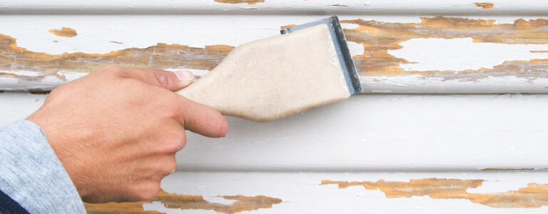 person scraping lead based paint off a wall