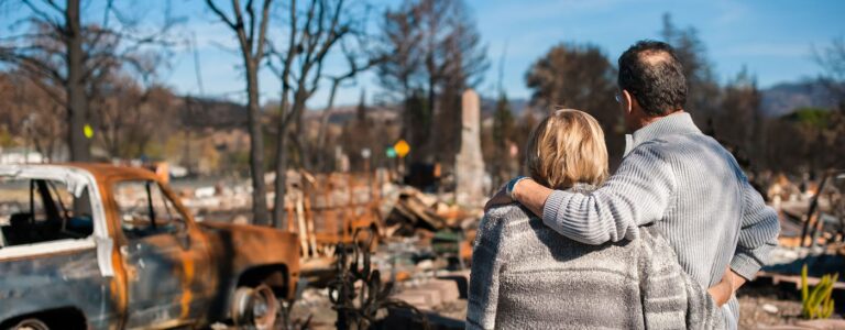 couple and looking at a burned down house