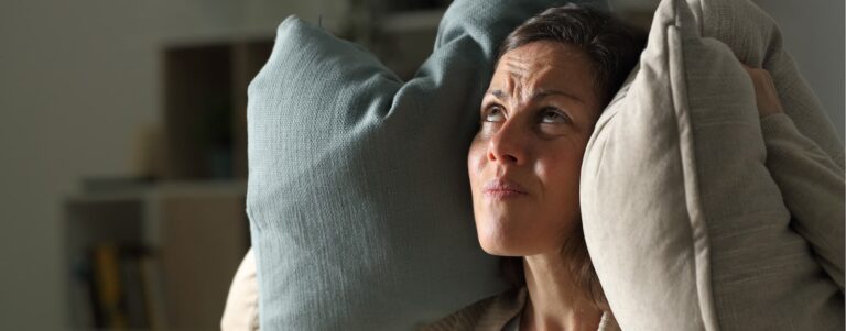 woman covering her ears with pillows