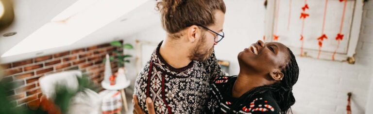 couple laughing while decorating their apartment for Christmas