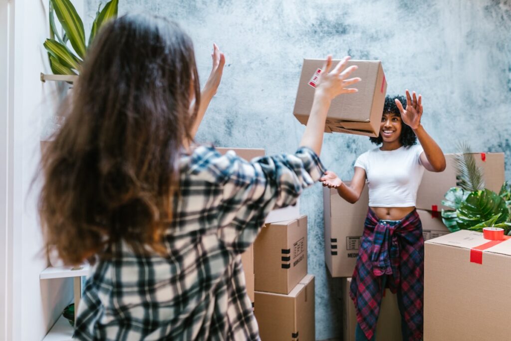 Two happy women throwing boxes while moving