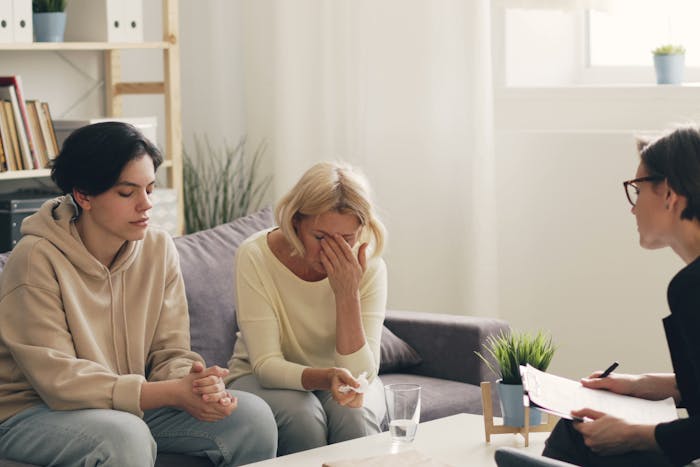 Three women sitting on a couch talking to each other