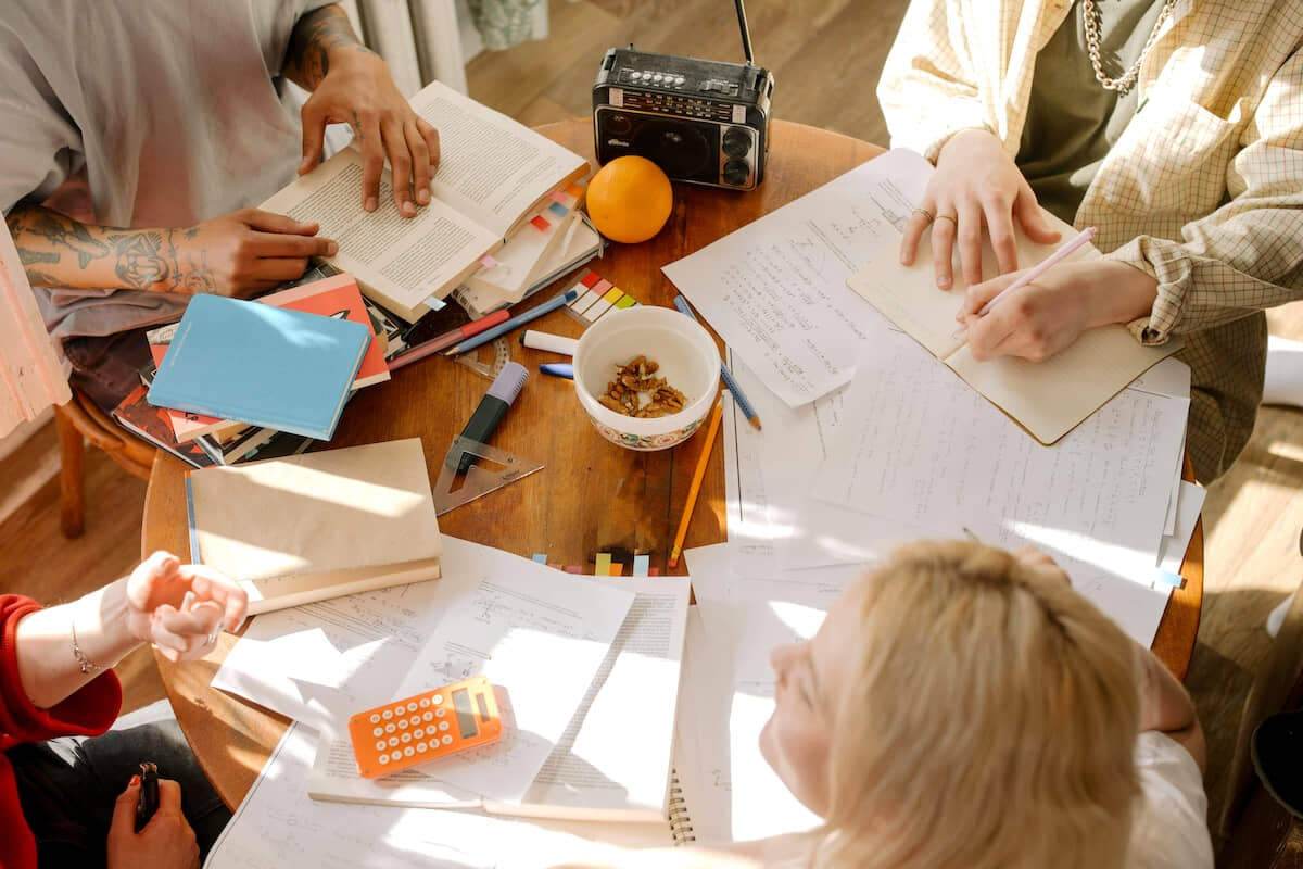 Roommates sitting at a table studying with their landlord